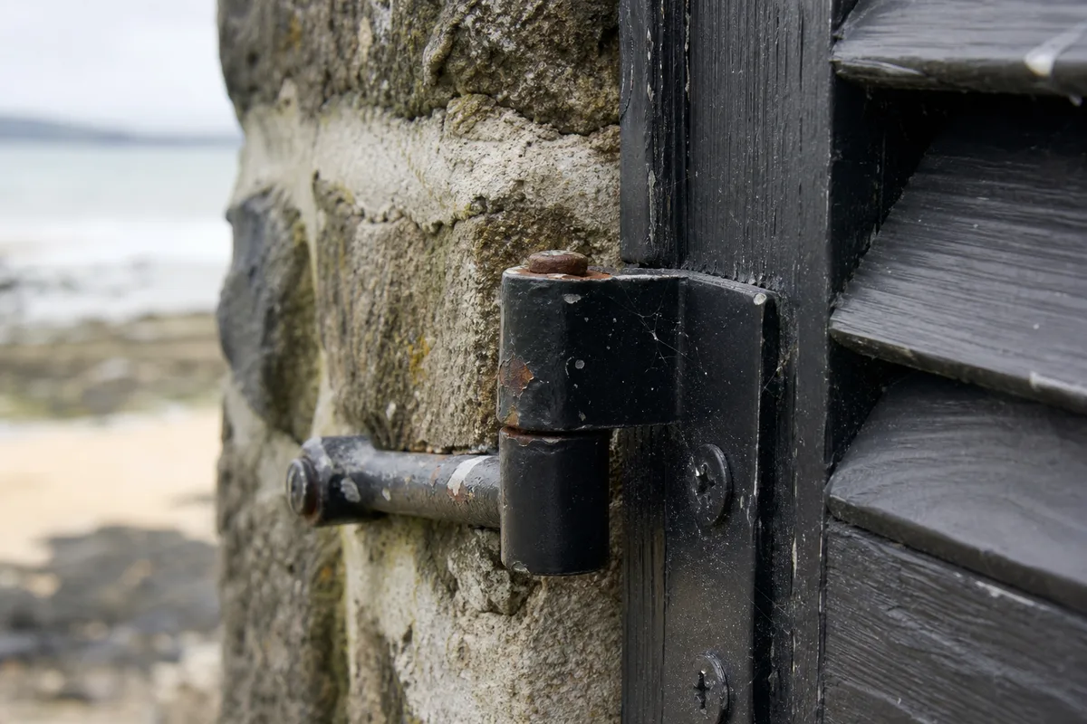 Détail d&rsquo;une paumelle en acier sur un volet pliant en bois peint d&rsquo;une maison nantaise